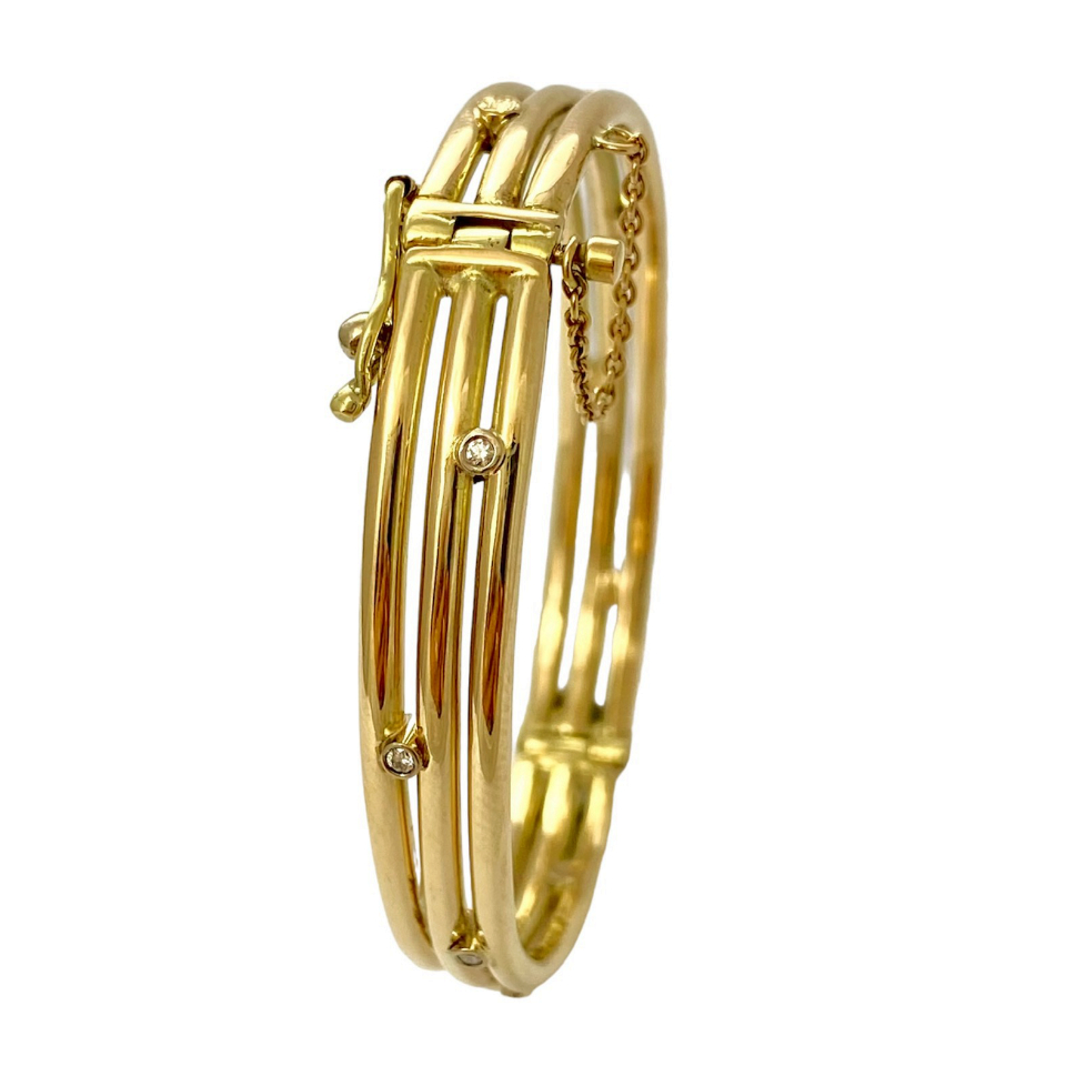 14 krt. opengewerkte gouden armband van rond draad, tussen de 3 banen zitten diamantjes in zetkastjes armband is een bangle